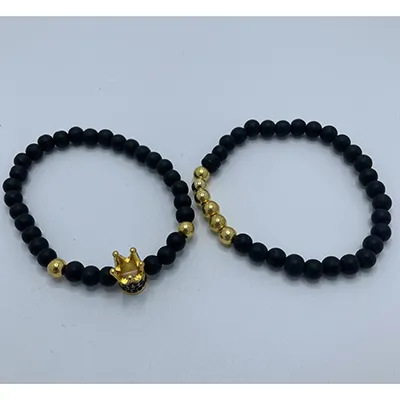 Pereche de brățări cu perle metalice negre vopsite și perle din plastic de culoare aurie. O coroană metalică împodobește una dintre brățări.