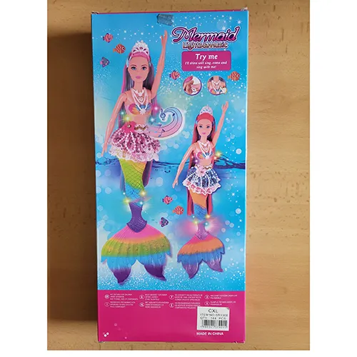 Păpușă cu păr lung și colorat, fustă din dantelă cu mărgele din plastic, corset din plastic colorat, perle din plastic pe g&acirc;t și aripioare de pește. Produsul include, de asemenea, un delfin din plastic &icirc;n roz sau albastru, o perie de păr, cochilii, scoici și o stea de mare. Dimensiune: 39 cm.