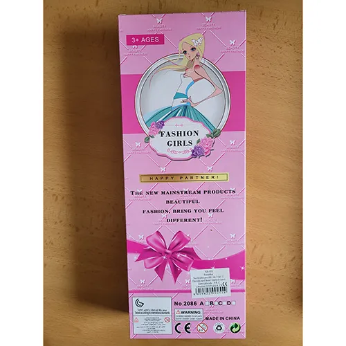Păpușă de plastic de aproximativ 29 cm înălțime, cu o geantă de mână din plastic violet, păr lung blond împletit purtând un capac alb și o rochie medicală albă.