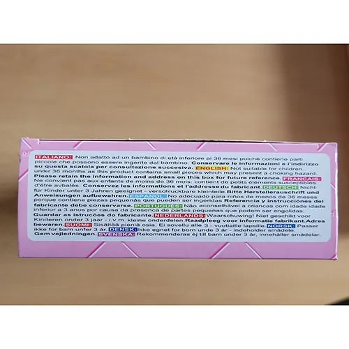 Păpușă de plastic de aproximativ 29 cm înălțime, cu o geantă de mână din plastic violet, păr lung blond împletit purtând un capac alb și o rochie medicală albă.