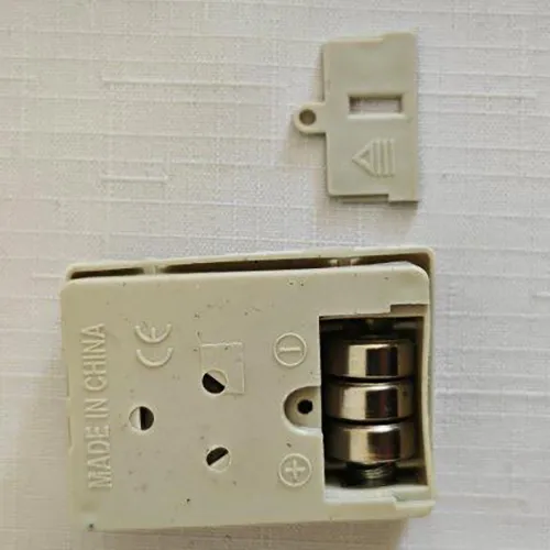 Păpușă textilă cu cap de plastic, mâini și pantofi. Păpușa are părul lung și blond și este îmbrăcată într-o rochie colorată și chiloți. Sub rochie, există un compartiment detașabil pentru baterii pentru trei bucăți de baterii LR44.