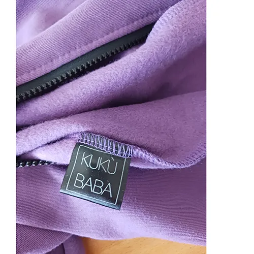 Salopetă pentru copii, confecționată din tricot violet, cu glugă, două buzunare pe față și un șnur cu capete libere, de aproximativ 31 cm lungime.