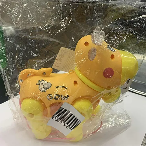 Funcționează cu baterii din plastic, are roți și un șir atașat. Jucăria este în formă de vacă, cu ochi și obraji pictați, coarne și un clopot transparent atașat la gât.