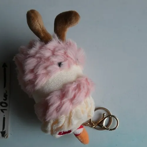 Breloc cu o jucărie moale &icirc;n formă de tort de ziua de naștere cu ochi de plastic și o &icirc;ncuietoare metalică aurie. Produs v&acirc;ndut online, &icirc;n special prin intermediul TikTok.