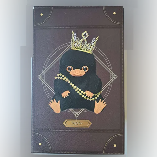 Jucărie moale, în formă de creatură Niffler, cu o coroană aurie și un colier cu mărgele. Produs vândut online, în special prin intermediul Shein.