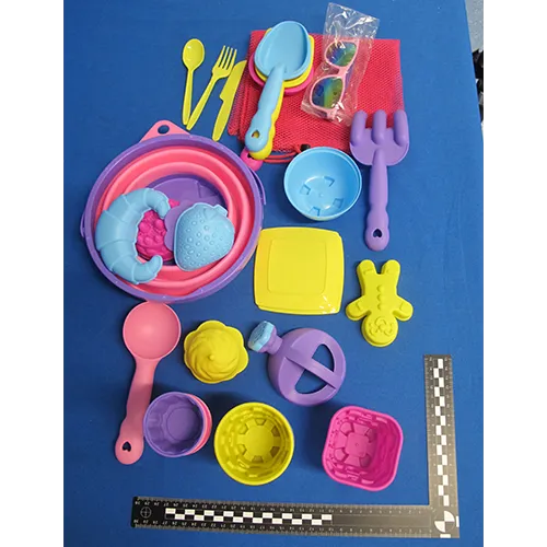 Set de jucării din plastic destinat plajei, format din 31 de părți, inclusiv o găleată pliabilă, un set de tac&acirc;muri (cuțite, furculițe și linguri), o plasă, ochelari de soare, o cutie de udare, cinci unelte, două plăci și 17 forme. Produs v&acirc;ndut online, &icirc;n special prin intermediul Amazon (ASIN B0DSVW25YQ).