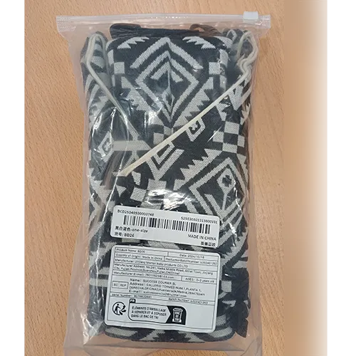 Purtător pentru copii realizat din țesătură albă cu modele negre și un dispozitiv de fixare din plastic.