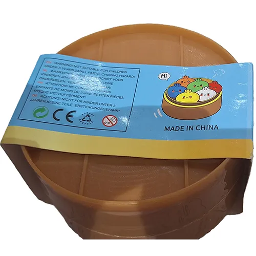 Str&acirc;ngeți jucăria &icirc;n formă de găluște chinezești &icirc;ntr-un recipient de plastic făcut să semene cu un vapor de bambus.