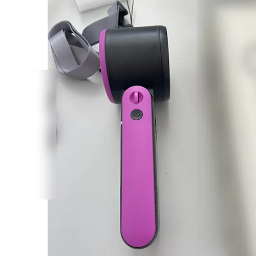Ventilator pliabil portabil re&icirc;ncărcabil, cu o carcasă din plastic &icirc;n negru și roz, v&acirc;ndut cu un cablu de &icirc;ncărcare USB și o curea de &icirc;ncheietură.