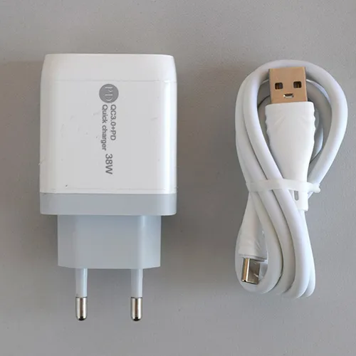 &Icirc;ncărcător USB alb cu un port USB-A și un port USB-C, furnizat cu un cablu de conectare USB separat. Intrări: 100-240V, 50-60Hz, 0,35A. Realizare: 5V/3A, 9V/2A, 12V/1.5A.