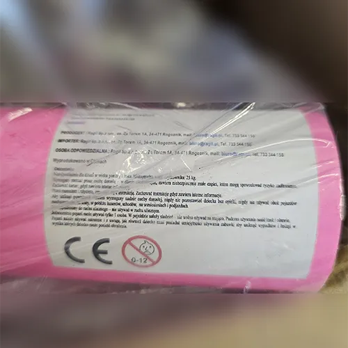 Tricicletă pentru copii, roz, cu pedale pe roata din față, un coș atașat la ghidon, un coș atașat la spate și un mâner de împingere.